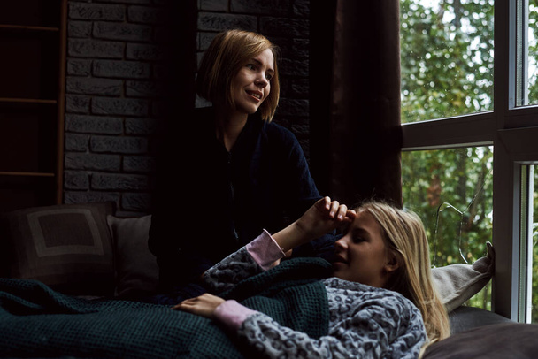 Mom with her teenage daughter are lying on the bed. The relationship of mother and child. - Fotoğraf, Görsel