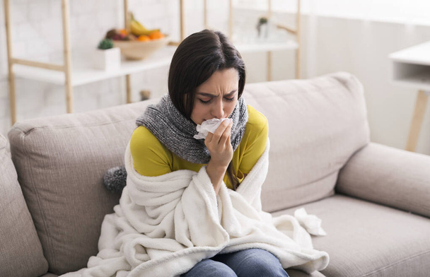 Infectious disease. Lovely girl wrapped in warm blanket suffering from virus at home - Фото, изображение