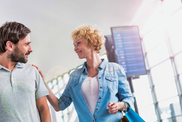 Portrait of mature couple walking while talking in airport - Photo, image