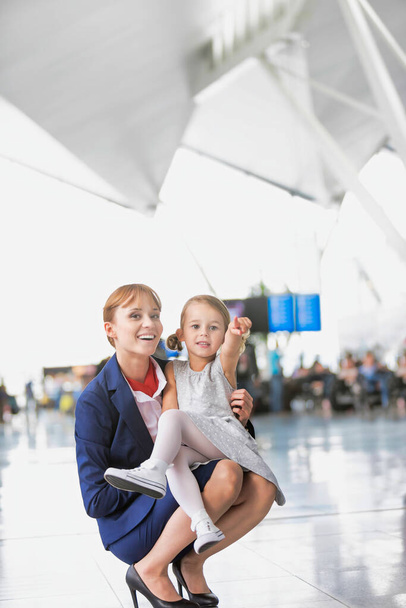Young attractive airport staff talking to cute little girl in airport - Photo, image