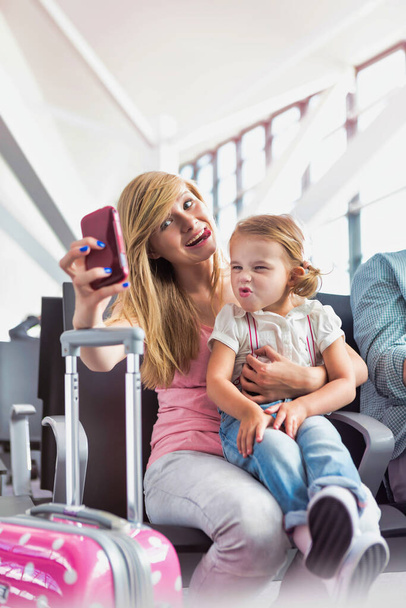 Portrait of young teenage girl taking selfie with her little sister while waiting for boarding in airport - Valokuva, kuva