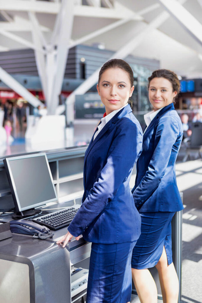 Portrait of young attractive passenger service agents standing in airport - 写真・画像