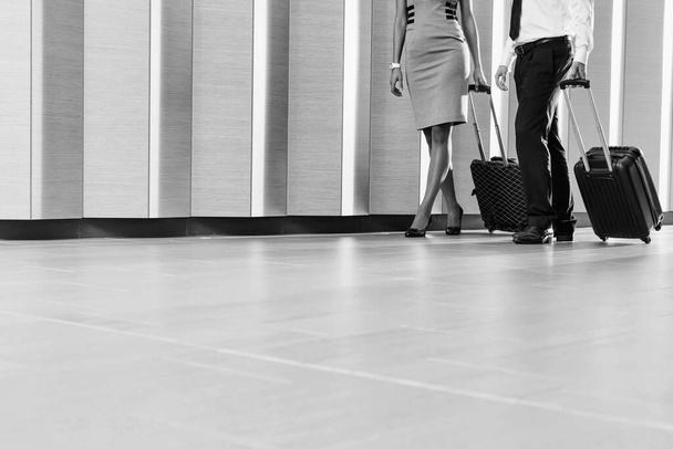 cropped image of Businessman and businesswoman walking with travel bags in hotel - Foto, imagen