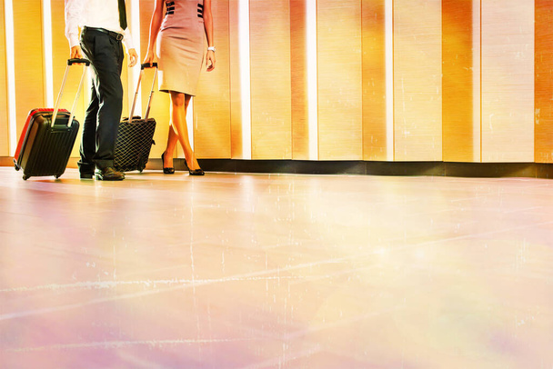 cropped image of Businessman and businesswoman walking with travel bags in hotel - Zdjęcie, obraz