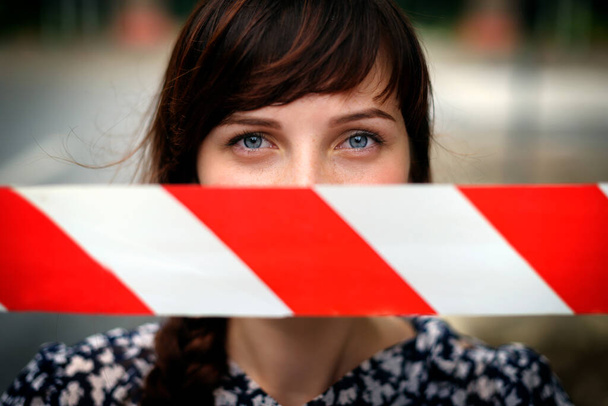 Close up gezicht van jonge mooie droevige Europese vrouw met mond verzegeld op gevaarlijke tape met de rode en witte strepen. Het idee om geen leugens te vertellen. Verboden onderwerp concept foto - Foto, afbeelding