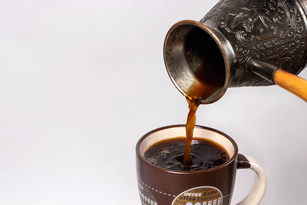 Café preto de manhã. O processo de despejar café expresso, americano de cobre turk em uma xícara de café. Os benefícios e danos do café. O efeito do café no corpo humano, pressão arterial e desempenho
. - Foto, Imagem