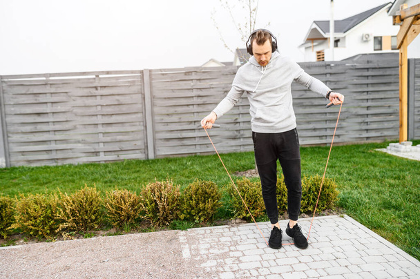 Guy with a headphones jumps with skipping rope - Photo, image