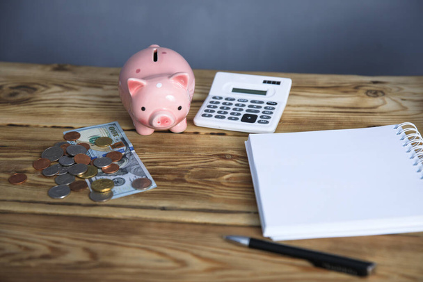 notepad with coins and piggy bank on tabl - Φωτογραφία, εικόνα