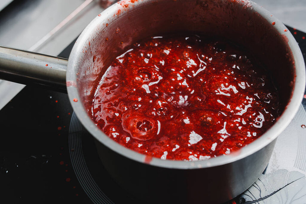 Boiling strawberry puree in a saucepan, close up - Fotó, kép