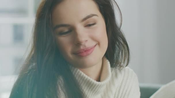 Beautiful Young Woman Using Smartphone Happily, while Sitting on the Chair. Sensual Girl Wearing Knitted Sweater Surfs Internet, Posts On Social Media, Sharing Picture while Relaxing in Cozy Apartment - Filmagem, Vídeo