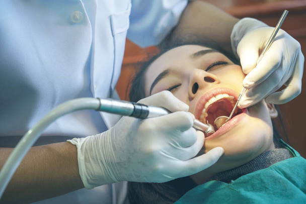 Uma mulher a fazer um exame aos dentes nos dentistas. Dentista e lindo paciente sorriso de dente no escritório. Jovem feliz na clínica de estomatologia com o Doutor. Paciente feliz e dentista com conceito de dentes saudáveis
 - Foto, Imagem