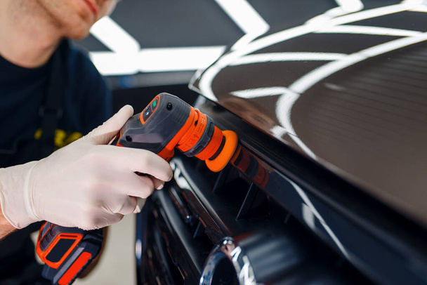 Férfi munkás polírozza radiátor rács segítségével polírozó gép, autó részletező közelkép. Előkészítésa telepítése előtt bevonat, amely védi a festék az autó a karcolásoktól, auto tuning - Fotó, kép