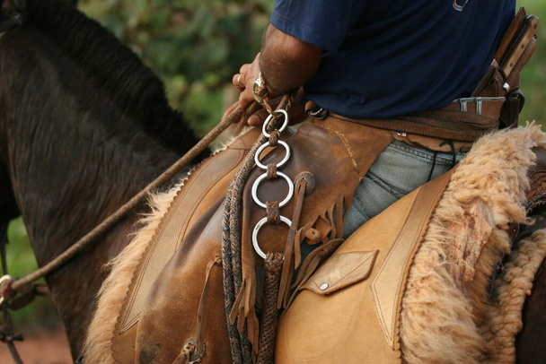 detail van cowboy outfit gemonteerd op paard zadel - Foto, afbeelding