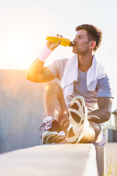 Portrait of young attractive man sitting while drinking energy drink - Foto, afbeelding