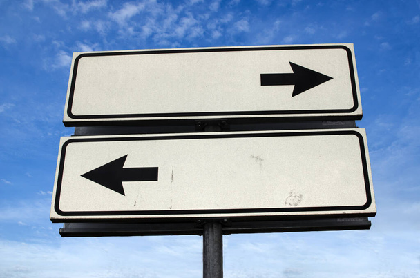 Crossroads Road Sign, Due frecce su sfondo cielo blu. Segnaletica stradale bidirezionale con spazio per la copia. Due frecce su un palo che puntano in direzioni diverse
 - Foto, immagini