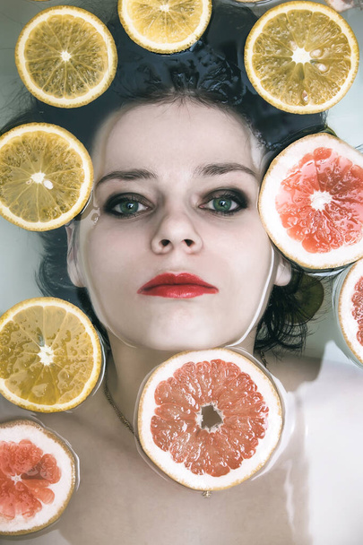 Portrait of a girl in the water with fruits - Photo, Image