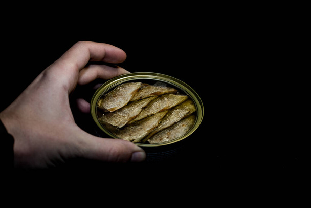 Espadines de pescado enlatados en un frasco y fondo negro
 - Foto, Imagen