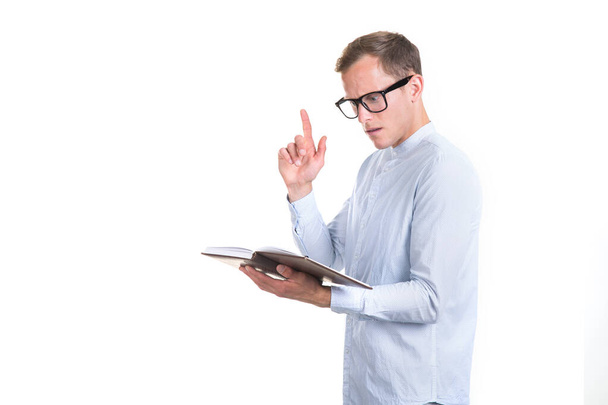 Idea! Young smart man in glasses with a book in his hands raised his finger up, isolated on a white background. - Foto, immagini