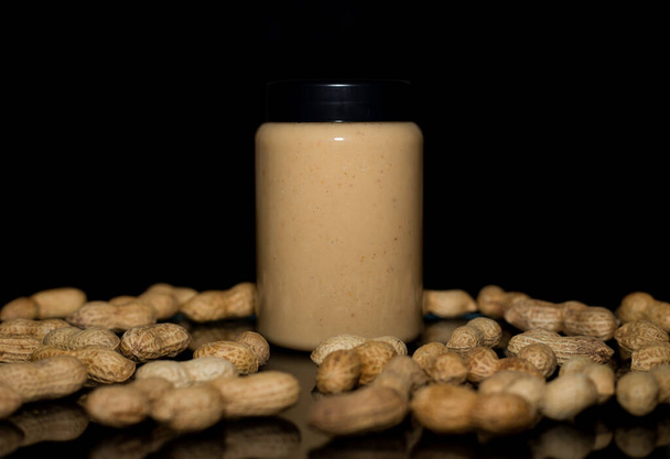 Спелые арахис в шелухе и банку с арахисовым маслом
 - Фото, изображение