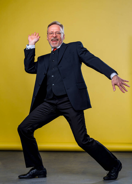 Senior manager man dancing at funny pose with expression. Yellow background. - Fotografie, Obrázek