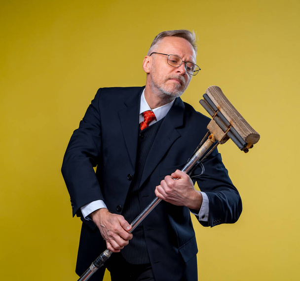 Adult man singing in mop. Holding broom like microphone. Man in suit. - Photo, image