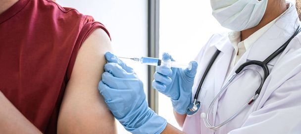 Lékař provádějící očkování pacienta s jehlou, který má v ruce imunitní vakcínu proti chřipce, koronavirovou ochranu proti epidemii. - Fotografie, Obrázek