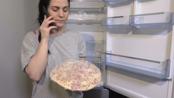  Nő tartja pizza közelében nyitott üres hűtőszekrény.Élelmiszer után a lejárati dátum koncepció - Felvétel, videó