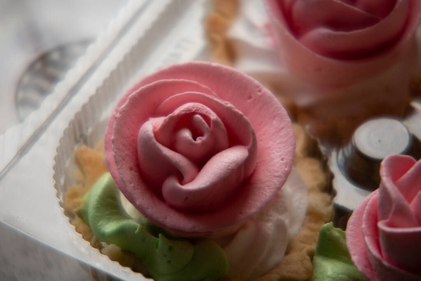 Cake Basket Rose. Food Photography, Dessert, Macro Photography. Van bovenaf close-up van vers gebakken cupcakes gevuld met bessen ganache wordt versierd met roze boterroom glazuur uit gebak zak - Foto, afbeelding