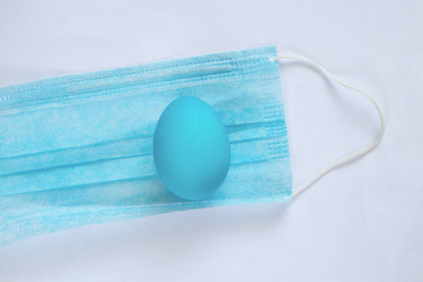 orvosi maszk és rajta fekszik egy húsvéti tojás húsvéti alatt - Fotó, kép