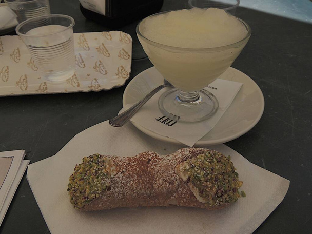 Sicilian cannolo served together with a crystal glass of Sicilian granita - Photo, Image