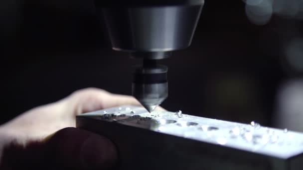 Скручені шматки надлишку металу злітають зі шматка алюмінію під час обшивки дрилем з ЧПУ. Дрібно нарізаний кінцевий млин для гоління збоку матового блоку металу
. - Кадри, відео