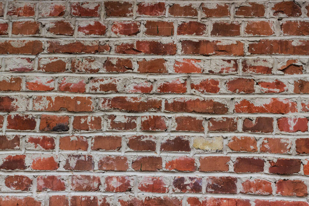 Old weathered red brick wall as a background. The repeating texture of a red brick wall is often around the back of buildings in cities. Seamless texture file, brick background - Photo, Image