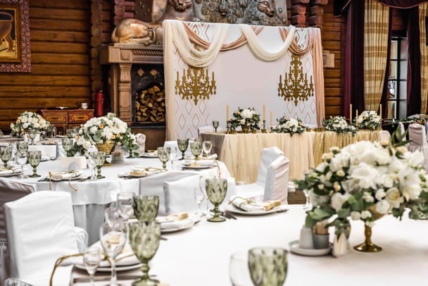 Witte bruiloft decoratie in restaurant. Luxe bruiloft arrangement. Bruiloft banket decoratie. Tafels in restaurant versierd met prachtige witte pioenen en rozen - Foto, afbeelding