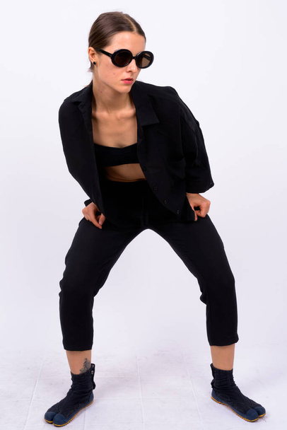 Studio shot of young beautiful woman as secret agent against white background - Foto, imagen