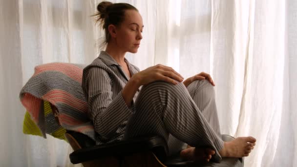 vrouw in pyjama mediteren op stoel - Video