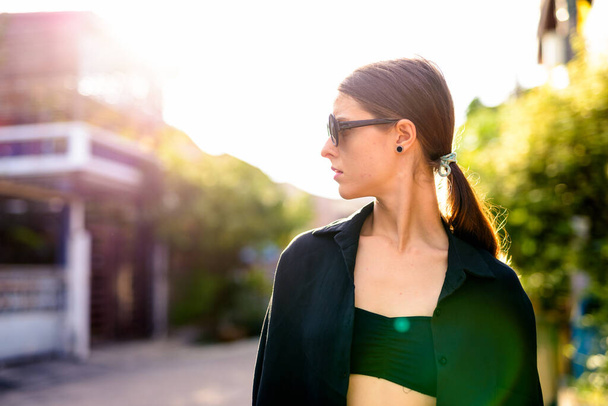 Portrait of young beautiful woman as secret agent in the city streets outdoors - 写真・画像