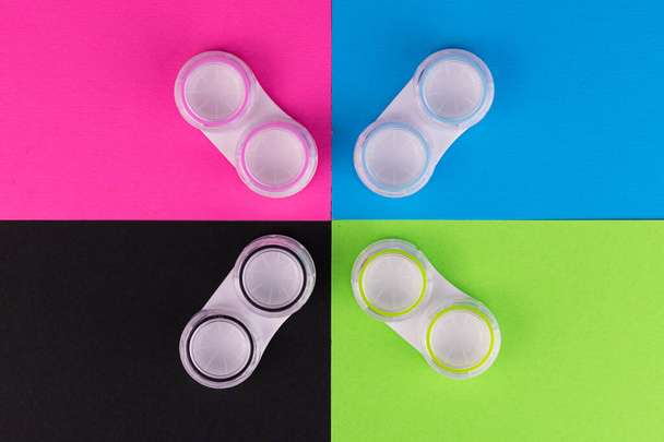 Kontejnery pro kontaktní čočky v různých barvách na barevném pozadí.Pohled shora. - Fotografie, Obrázek