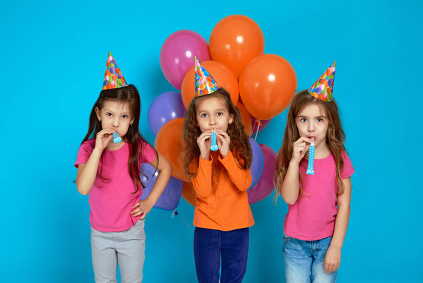 children in birthday hat with bright colorful air balloons blowing party horn - Foto, Imagem