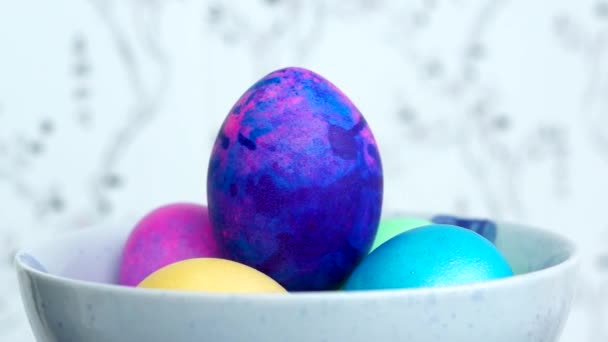 Los brillantes huevos de Pascua en un tazón giran lentamente sobre un fondo claro
 - Metraje, vídeo