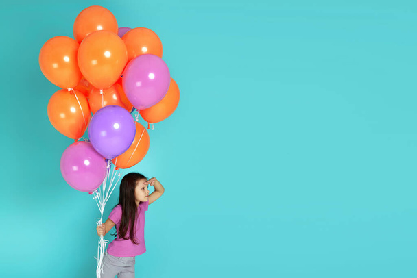 cute caucasian little child girl with colorful balloons looking far away with hand over head isolated on blue background. Searching concept. - Фото, изображение