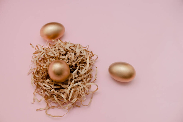 Velikonoční zlaté zdobené vejce v hnízdě na bílém pozadí. Minimální velikonoční koncept kopíruje prostor pro text. vodorovný pohled, plochý. - Fotografie, Obrázek