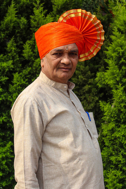 Старый индийский дедушка носит тюрбан оранжевого цвета и дает позу для фотографии
 - Фото, изображение