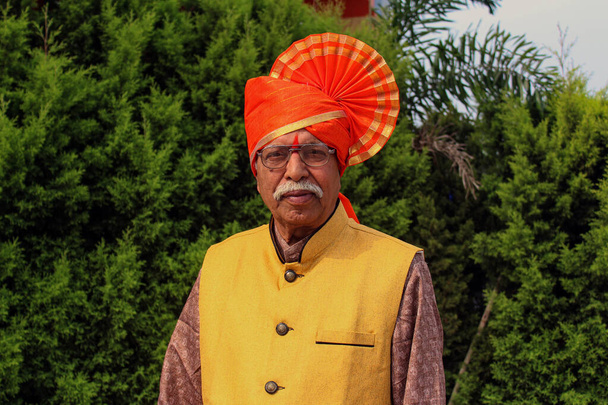 Vanha intialainen isoisä yllään oranssi väri turbaani ja antaa aiheuttaa valokuvan
 - Valokuva, kuva