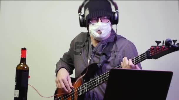 Man in a medical mask drinks wine and plays the bass. - Footage, Video