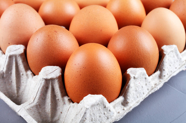 Chicken eggs in a paper tray on a gray background, close-up - Photo, Image