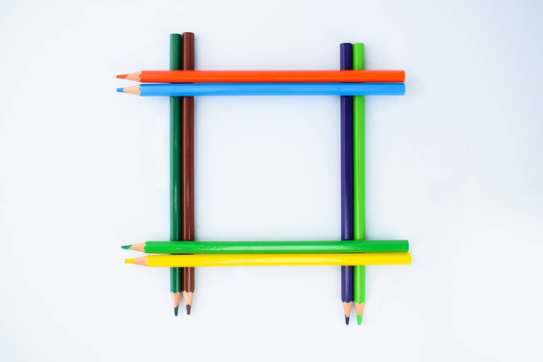 A Border-frame made of eight different colored pencil crayons isolated on a white background - Photo, Image