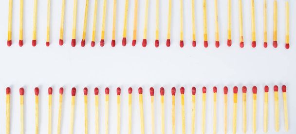 Two row's of red wooden match stick's facing each other arranged on a white background - Photo, image