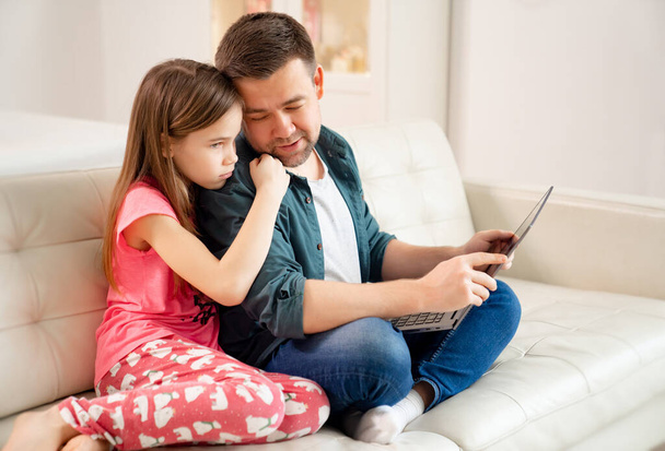 blogger and daughter work on Notebook on couch. - Foto, Imagem