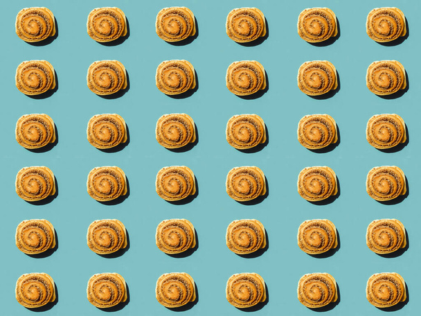 Sweet buns isolated on blue. Top view. Sweet cinnamon rolls pattern. hard shadow - Photo, Image