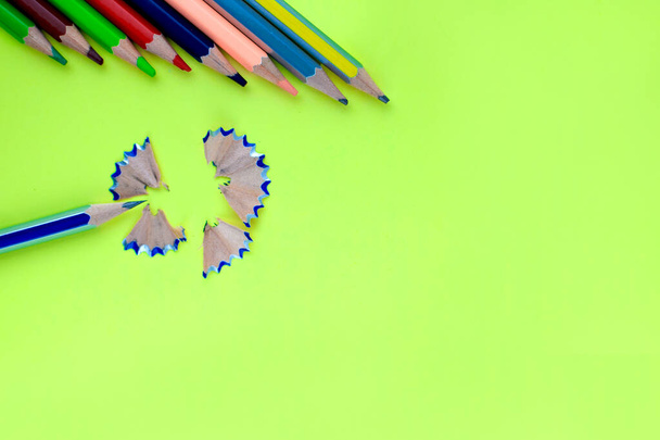 Diferentes lápices de colores de madera apuntando a un lápiz azul virutas sobre un fondo de papel amarillo
 - Foto, Imagen